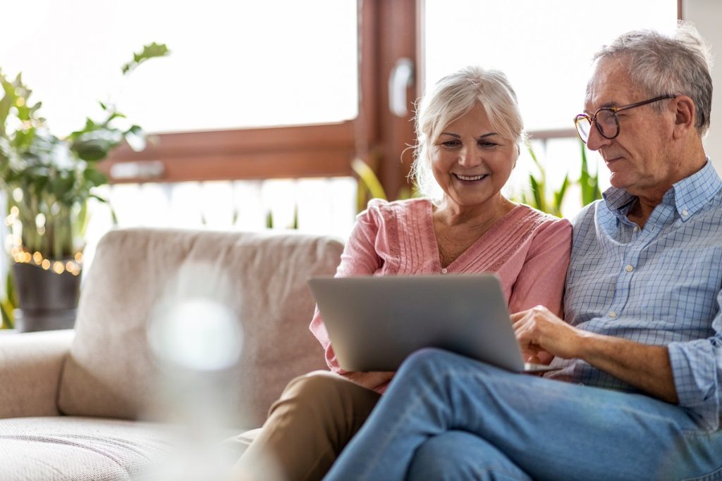 Senior couple using a laptop while relaxing at home.