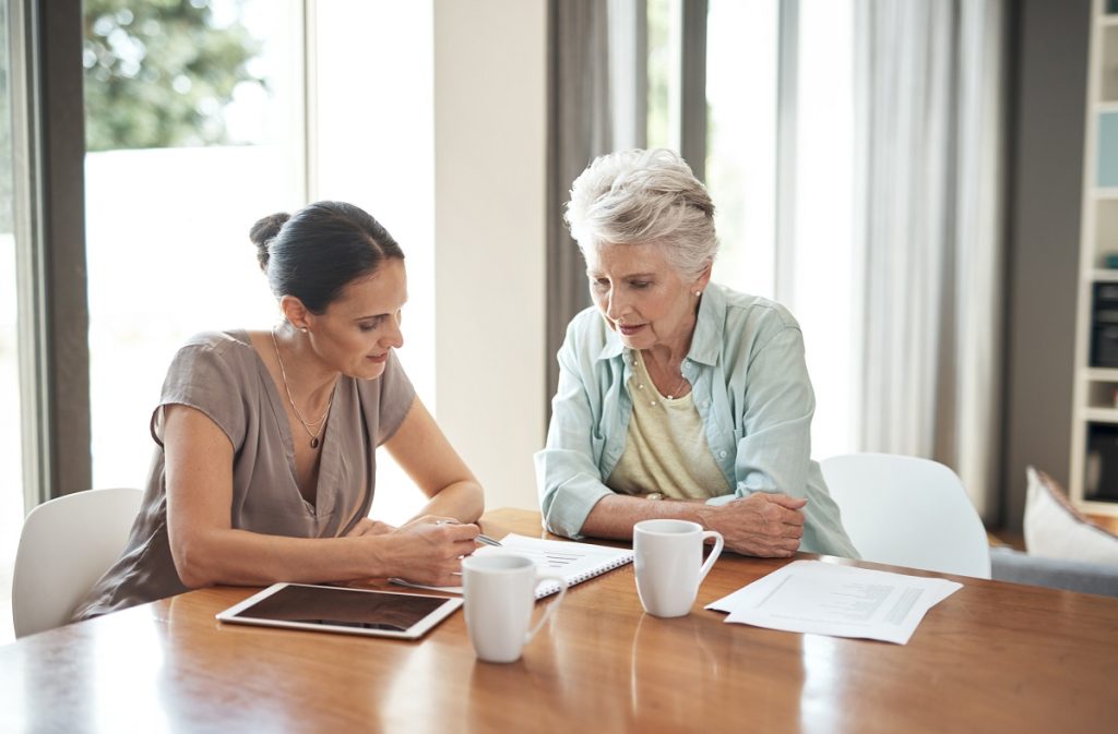 young woman assisting her elderly mother with her finances at home