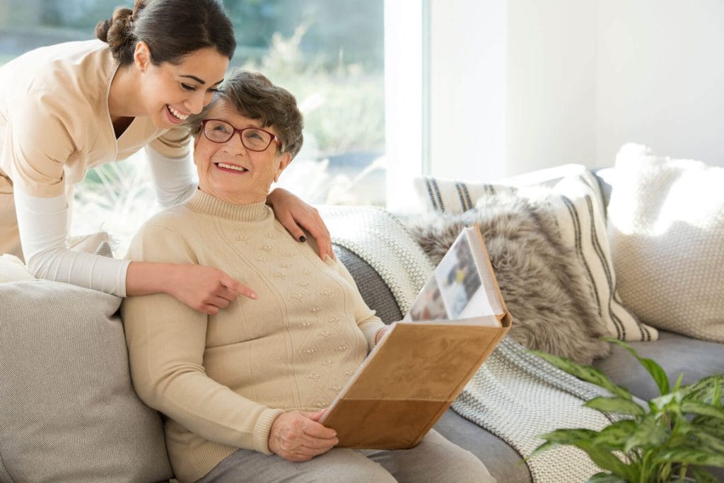 A woman and her nurse look at a photo album