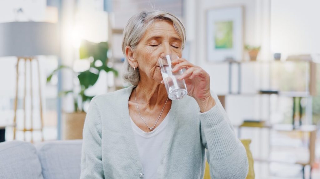 Older woman drinking water at home