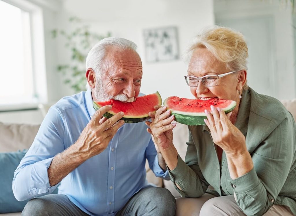 Couple of older adults eating watermelon