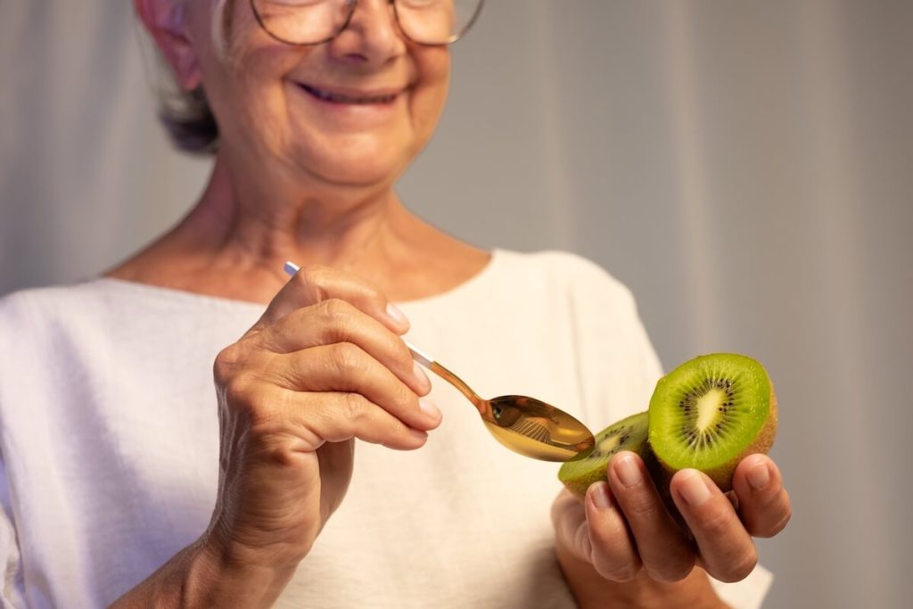 Smiling woman eating kiwi