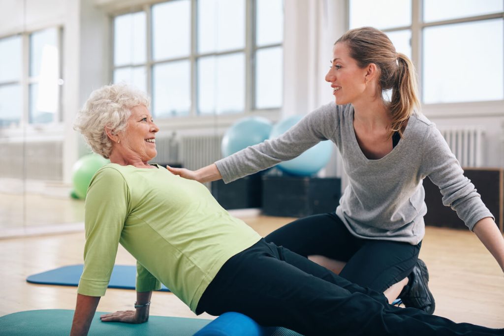 Caregiver helping woman do exercise.