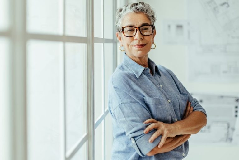 Empowered older woman posing by a window.