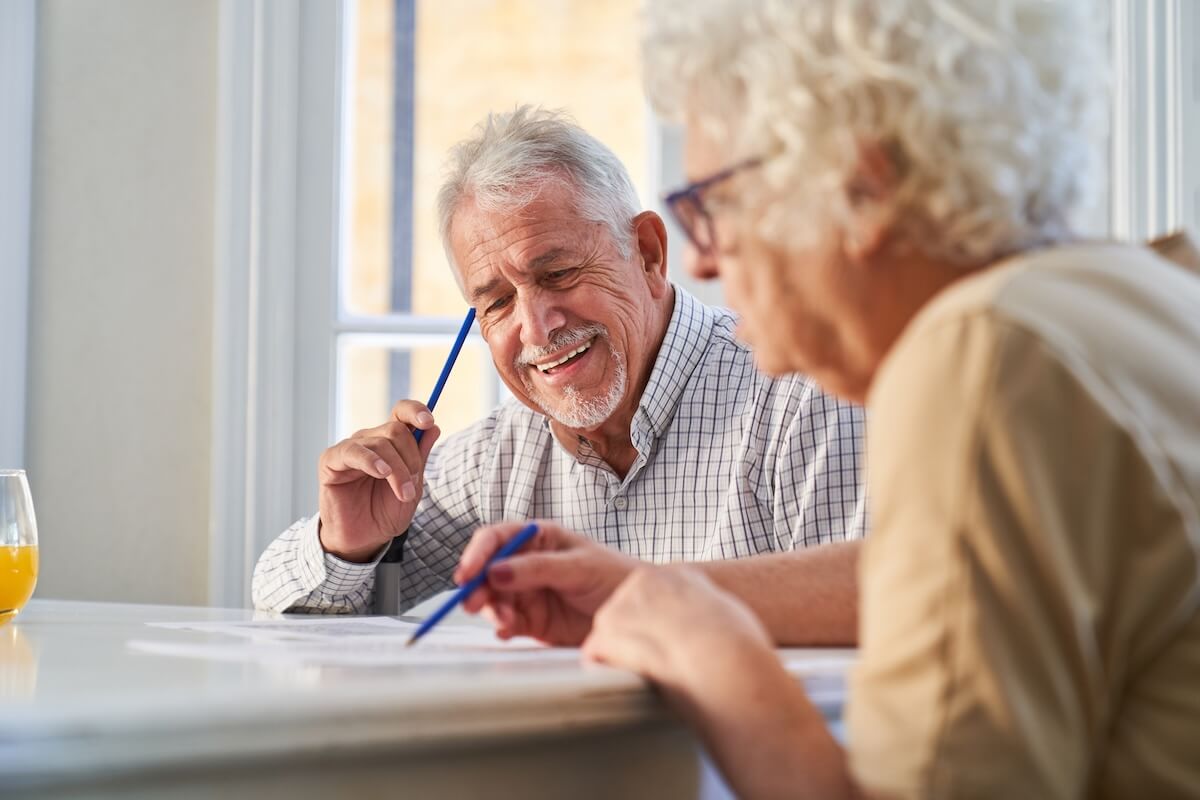 assisted living and memory care Couple of seniors has fun solving puzzles as a memory training against Alzheimer's and dementia